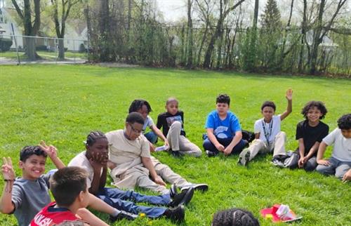  male students sitting on the grass